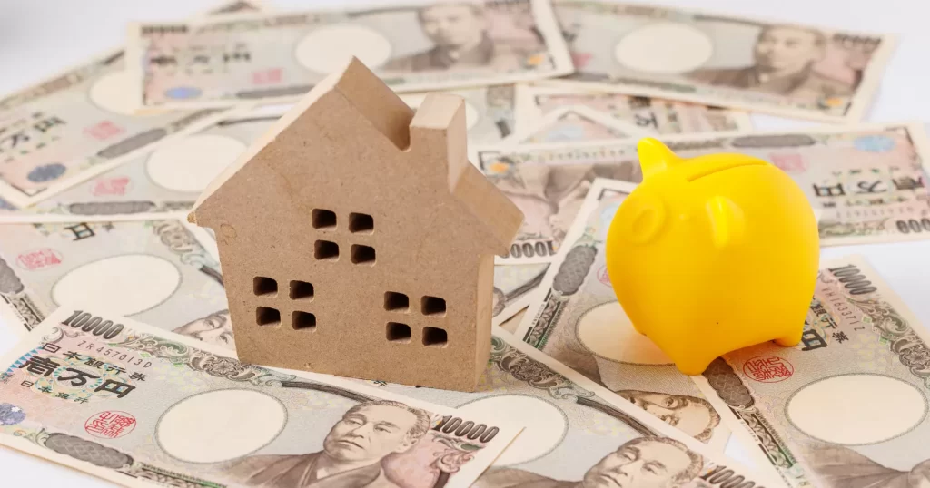 家の模型と紙幣、貯金箱