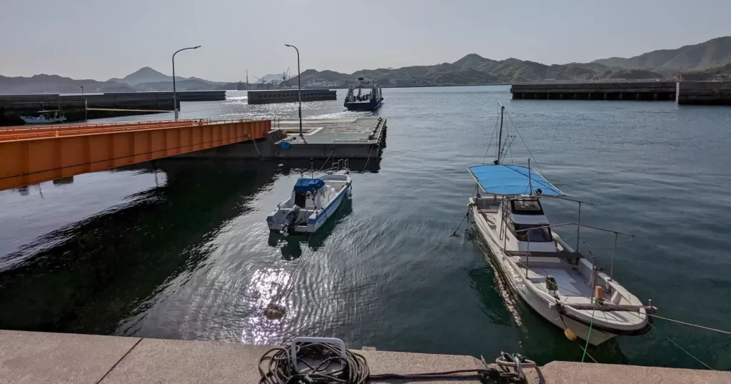 島の小さな港に停まる漁船と、沖へ出ていくフェリー
